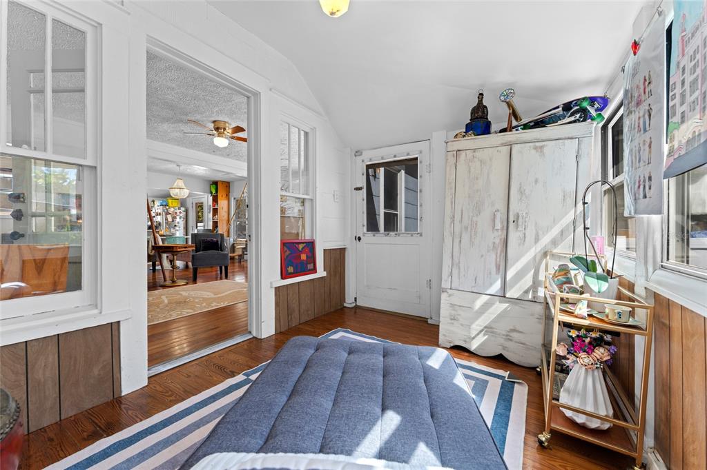 A sunroom with wood floors, a white cabinet, a blue floor cushion, and a bar cart — 783 30TH AVENUE N, ST PETERSBURG, FL