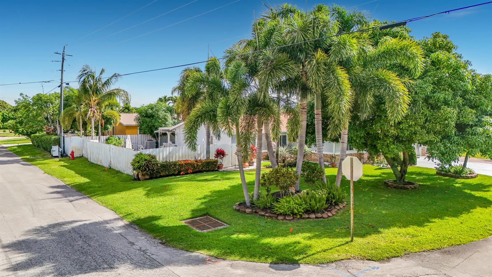 A residential property features a white fence, palm trees, and a lawn beside a road — 3119 Indian Trail, Lake Worth FL 33462, LAKE WORTH, FL