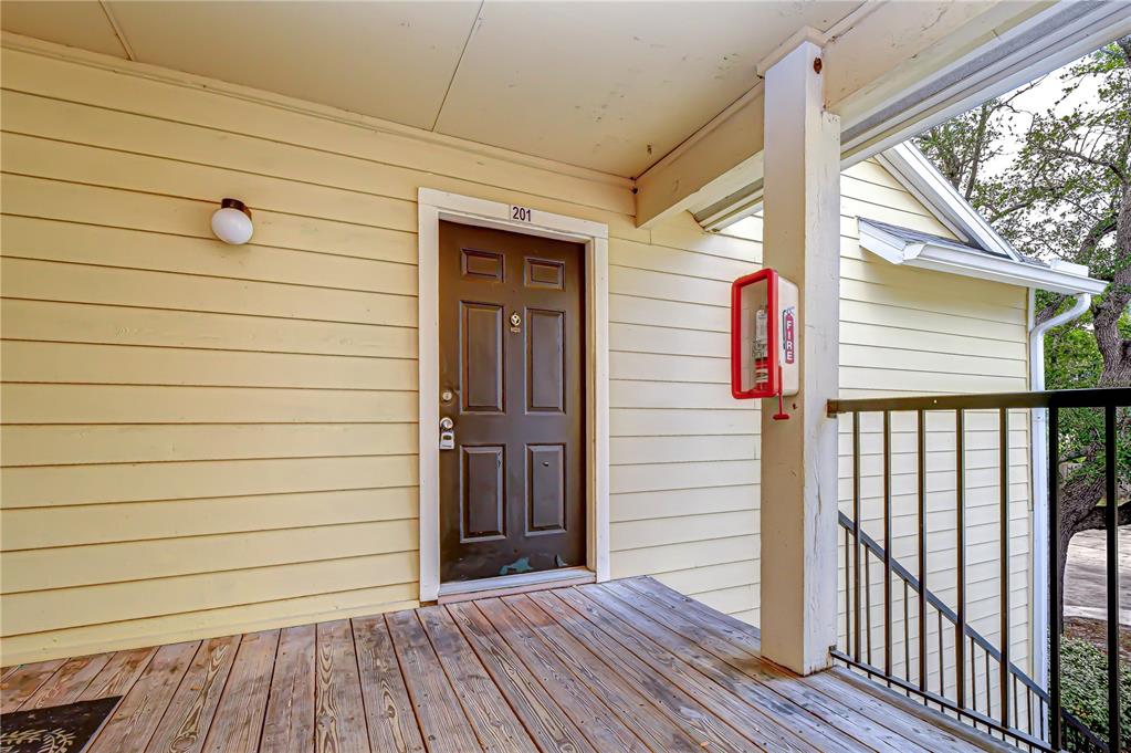 An exterior view of a brown apartment door labeled 201 on a wooden balcony — 8723 FANCY FINCH DRIVE UNIT 201, TAMPA, FL