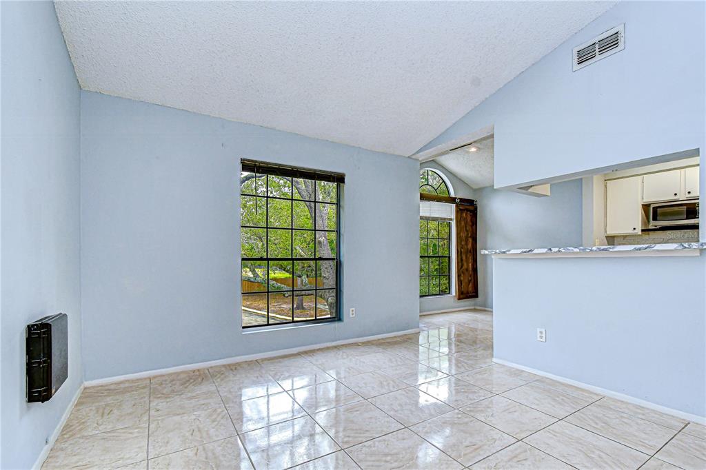 A bright room with light blue walls, tile flooring, and a large window — 8723 FANCY FINCH DRIVE UNIT 201, TAMPA, FL