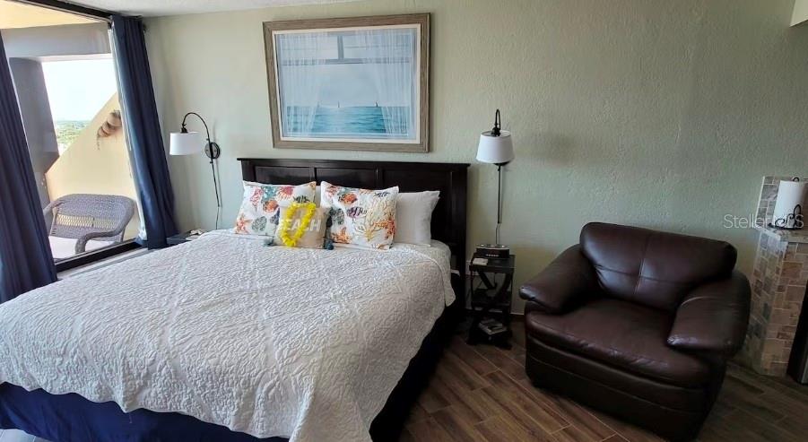 A bedroom features a queen bed, a brown leather armchair, and a balcony view — 2301 S ATLANTIC AVENUE UNIT 542, DAYTONA BEACH SHORES, FL
