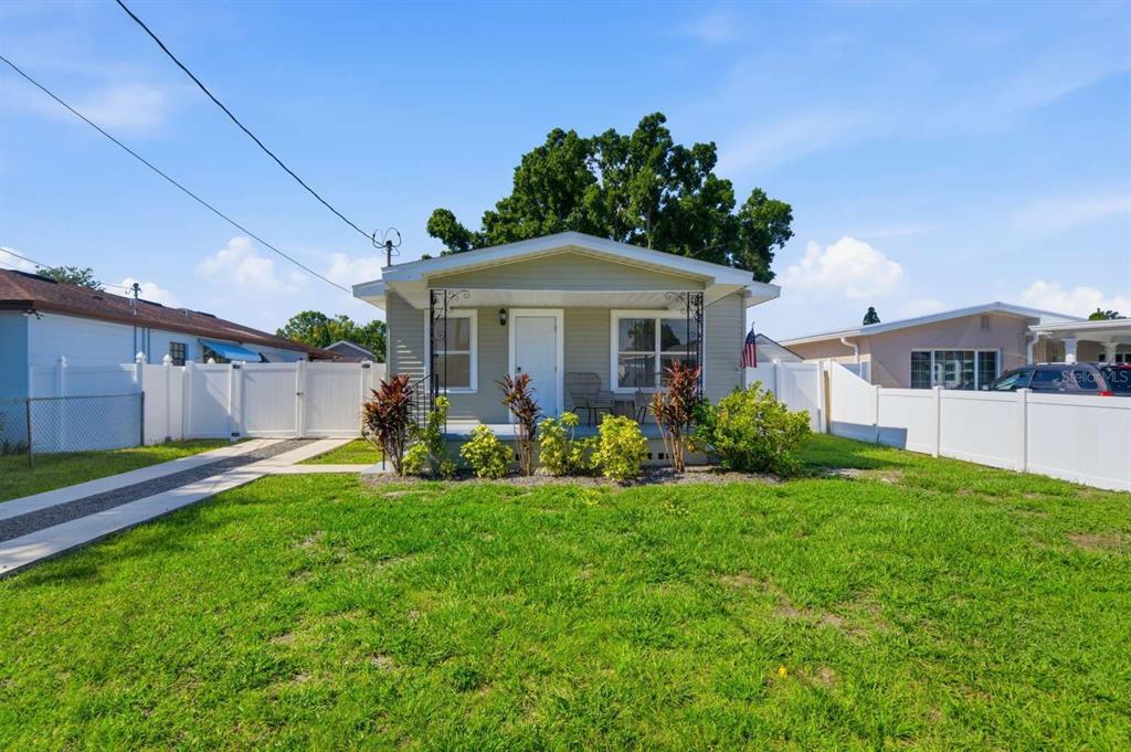 A small, light-green single-story house with a front porch and white vinyl fencing — 2704 W LEROY STREET, TAMPA, FL