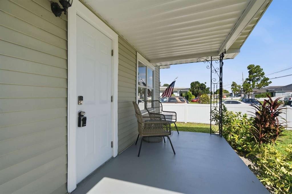 A covered front porch features light green siding, a white door, and two wicker chairs — 2704 W LEROY STREET, TAMPA, FL