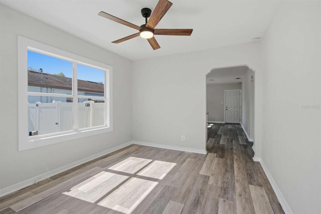 A room with light gray walls, wood-look flooring, a ceiling fan, and an arched doorway — 2704 W LEROY STREET, TAMPA, FL