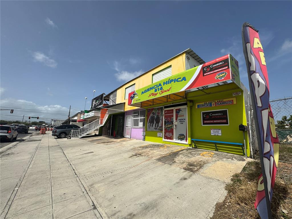 A yellow commercial building with a horse racing agency sign stands along a paved street — A13 GALICIA AVE.,, CAROLINA, PR
