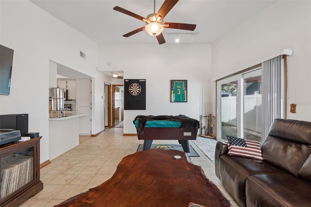 A living room features a pool table, a dartboard, a wooden coffee table, and tile flooring — 3134 WHISPERING DRIVE N, LARGO, FL