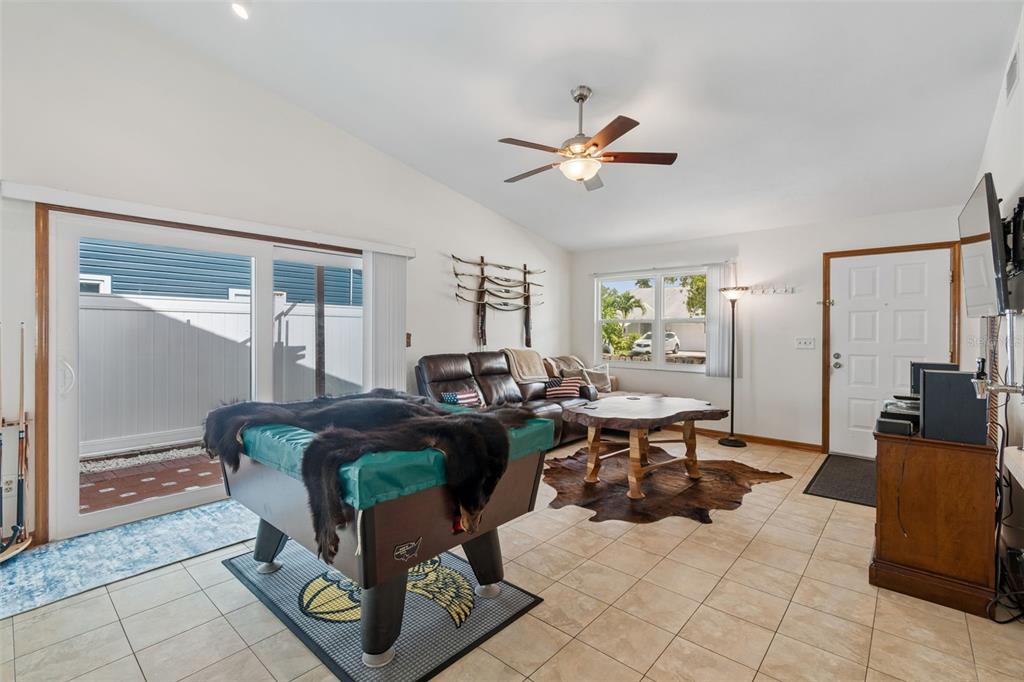 A living room features tile flooring, a pool table, a leather sofa, and a ceiling fan — 3134 WHISPERING DRIVE N, LARGO, FL