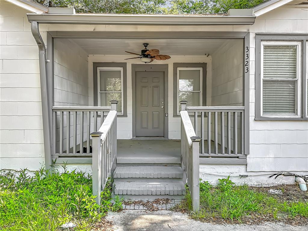 A covered front porch features gray wooden railings, a ceiling fan, and concrete steps — 3323 POST STREET, JACKSONVILLE, FL