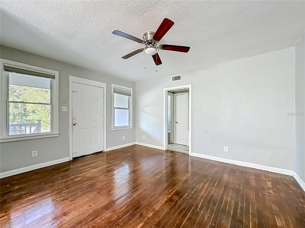 An empty room features hardwood floors, light gray walls, a ceiling fan, and two doors — 3323 POST STREET, JACKSONVILLE, FL