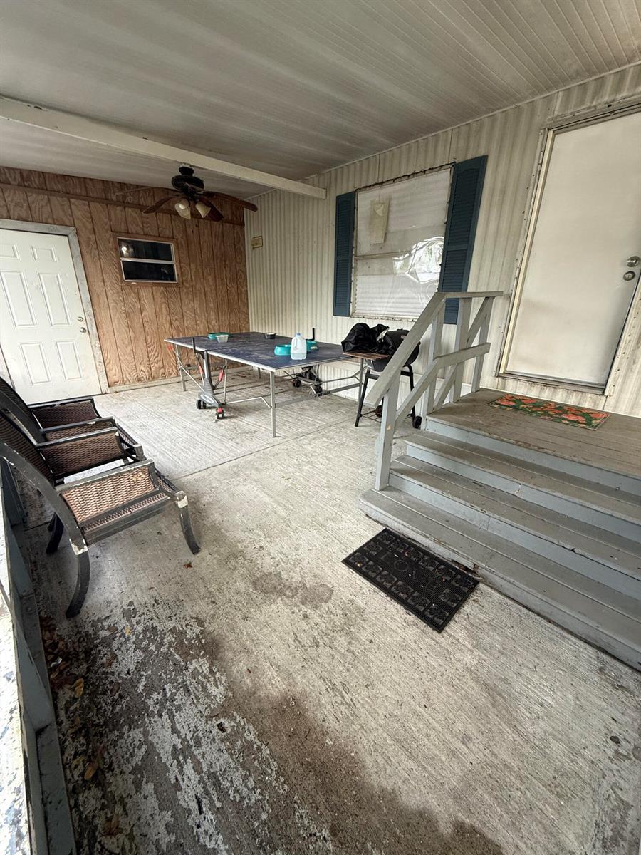 A covered concrete porch features a ping pong table, two chairs, and wooden stairs — 426 NE 31st Terrace, Okeechobee FL 34974, OKEECHOBEE, FL