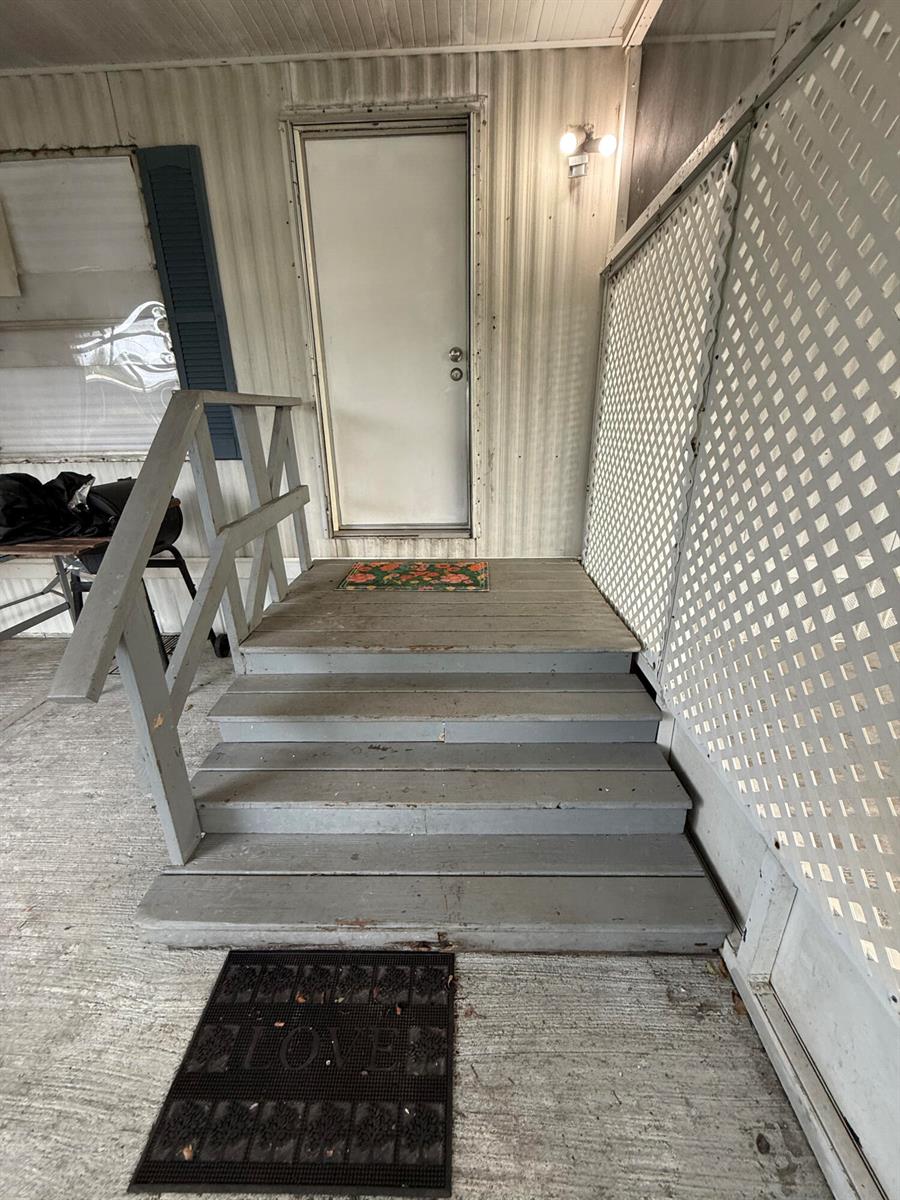 A set of gray wooden stairs leads to a white exterior door on a porch — 426 NE 31st Terrace, Okeechobee FL 34974, OKEECHOBEE, FL