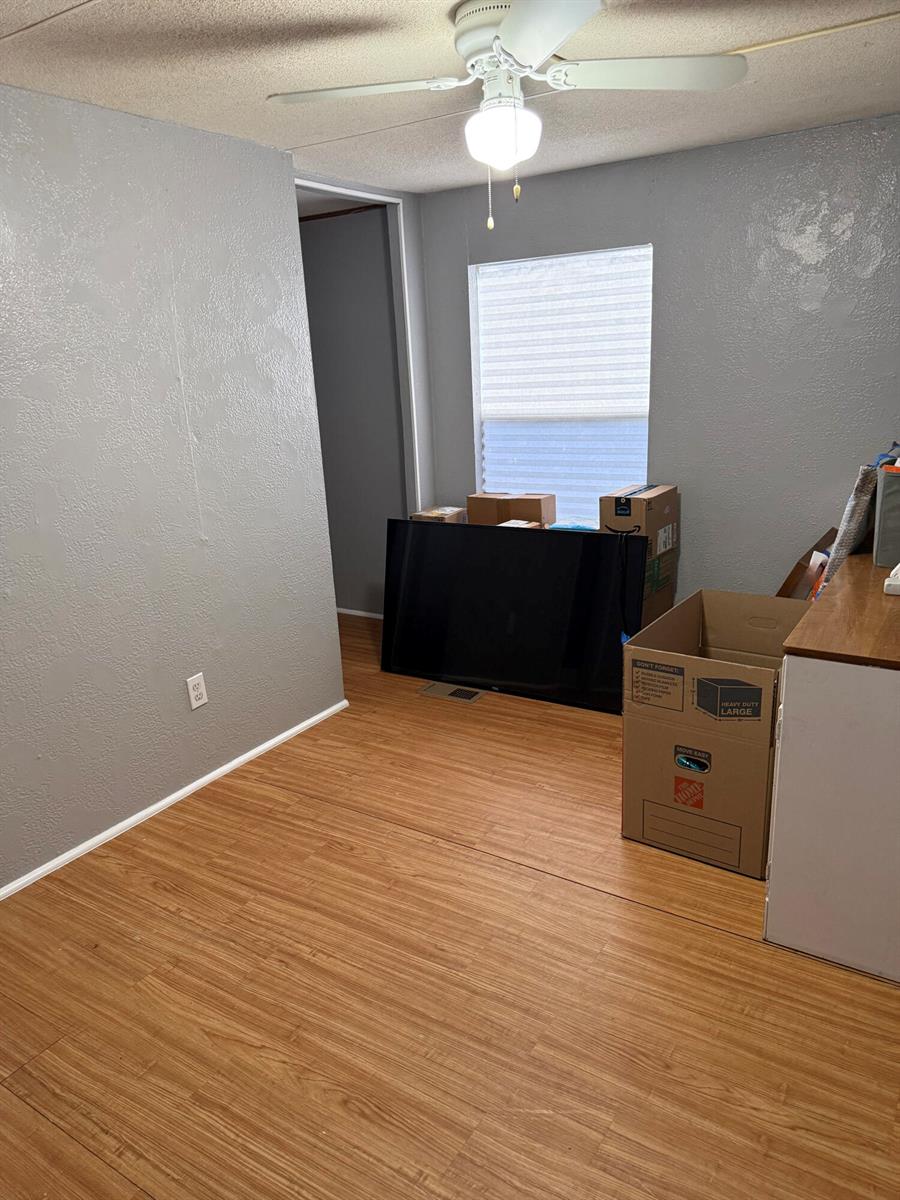 A room with gray walls, wood-look flooring, a ceiling fan, and moving boxes — 426 NE 31st Terrace, Okeechobee FL 34974, OKEECHOBEE, FL
