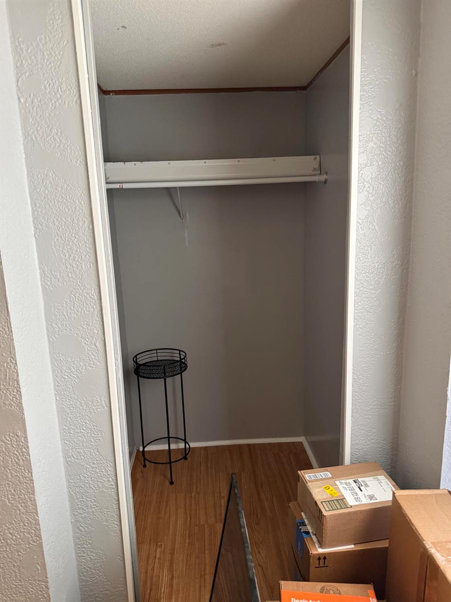 A small closet with gray walls, a single white shelf, and wood-look flooring — 426 NE 31st Terrace, Okeechobee FL 34974, OKEECHOBEE, FL
