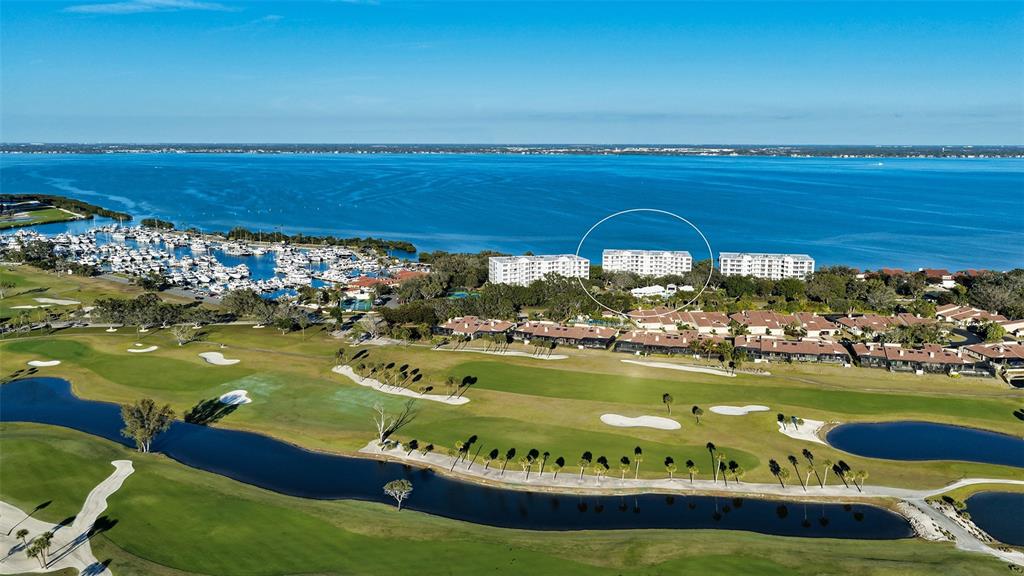 An aerial view shows a multi-story residential building circled near a marina and golf course — 2450 HARBOURSIDE DRIVE UNIT 234, LONGBOAT KEY, FL