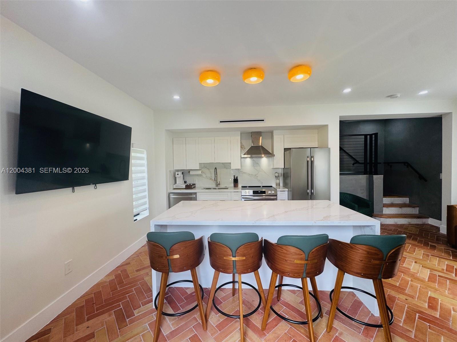 A kitchen features a white marble island, four wooden barstools, and herringbone brick flooring — 905 SW 13th Ct # 905, Miami FL 33135, MIAMI, FL