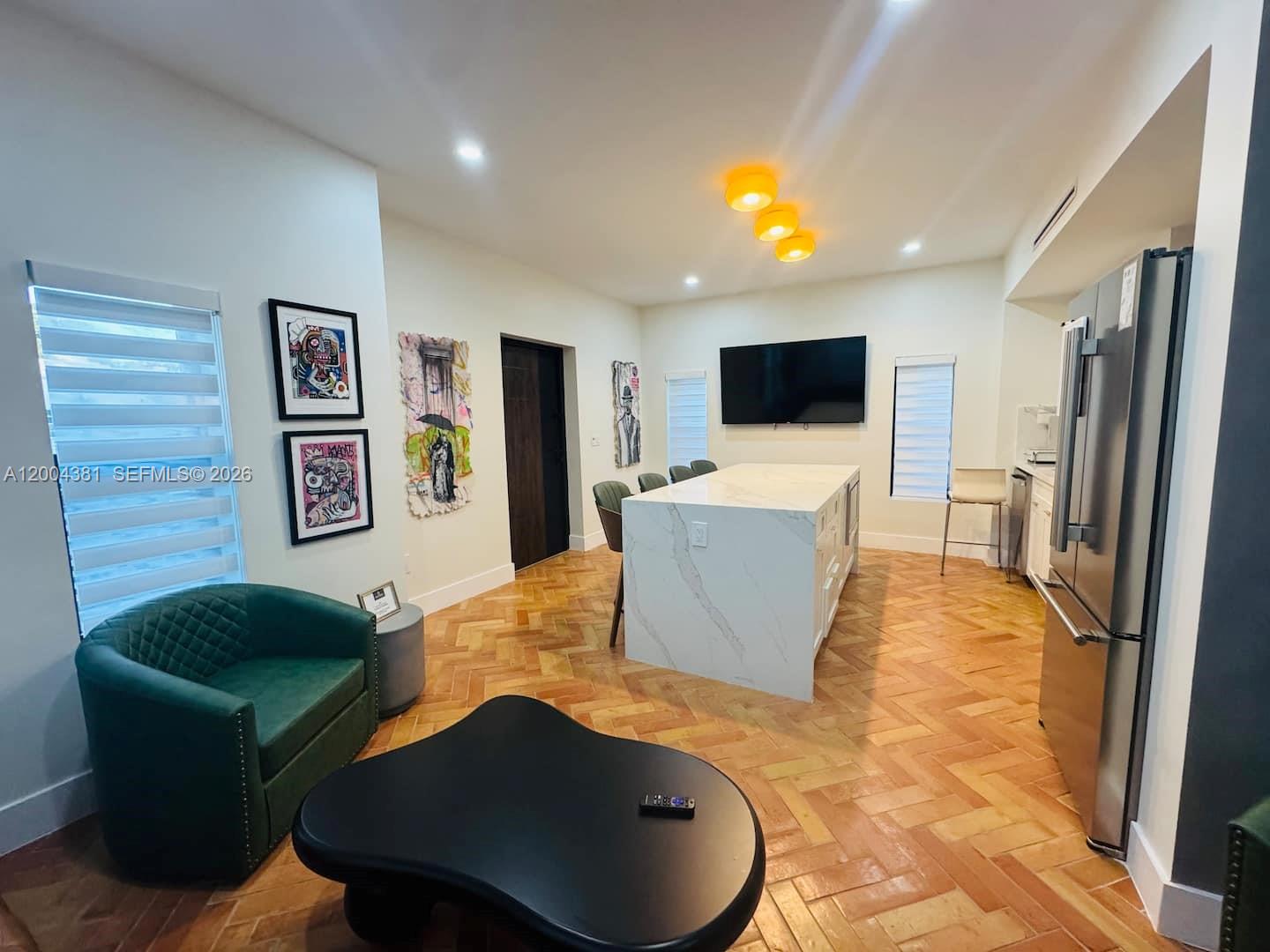 A kitchen and living area features a marble island, herringbone wood floors, and green seating — 905 SW 13th Ct # 905, Miami FL 33135, MIAMI, FL