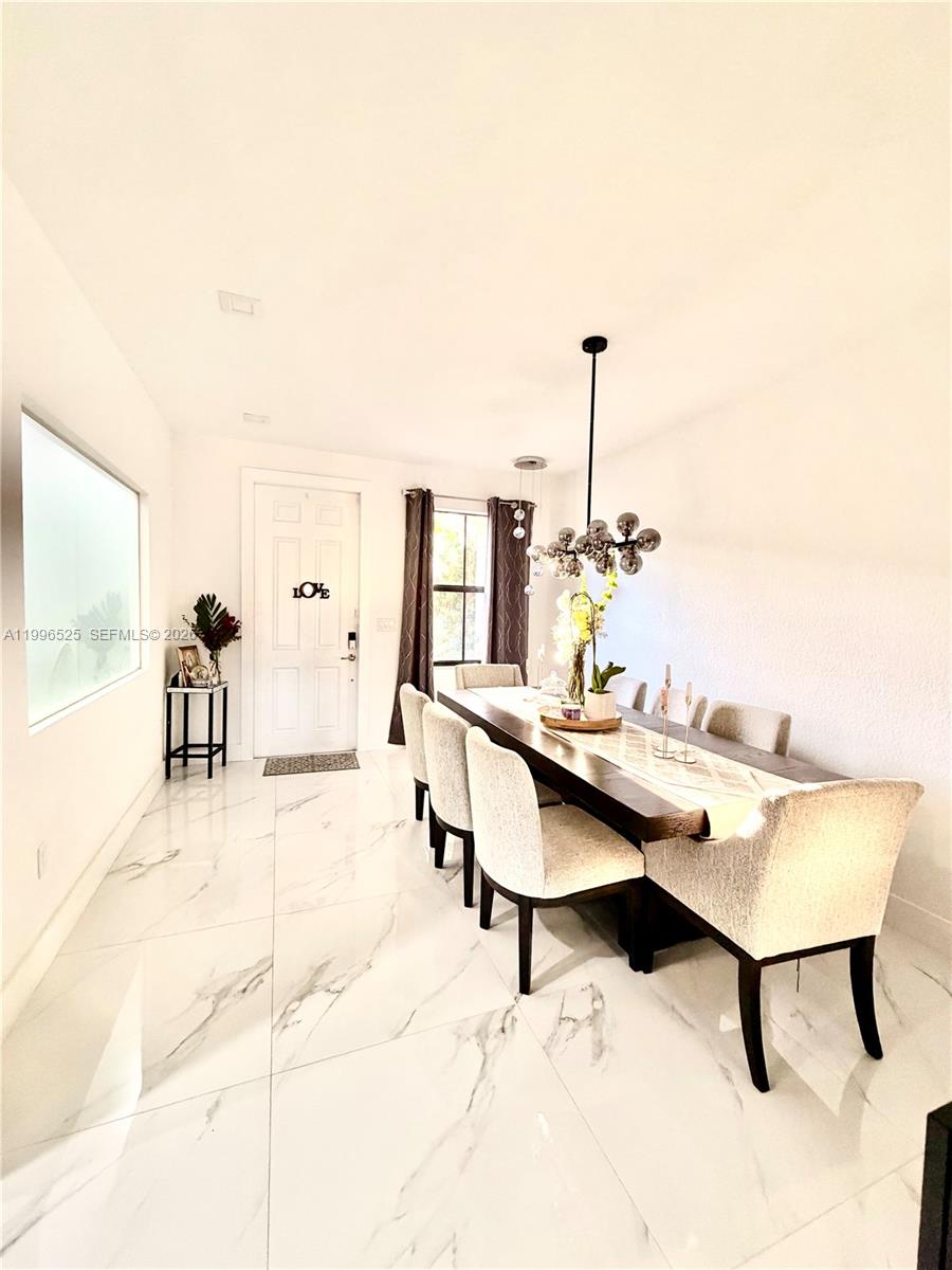 A dining room features a long wooden table, upholstered chairs, and white marble-look tile flooring — 4237 SW 164th Path # 4237, Miami FL 33185, MIAMI, FL