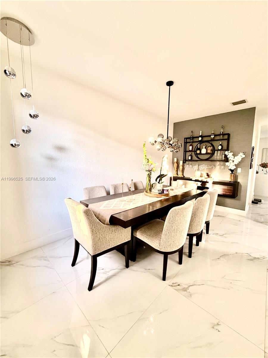 A dining room features a dark wood table, upholstered chairs, and a modern light fixture — 4237 SW 164th Path # 4237, Miami FL 33185, MIAMI, FL