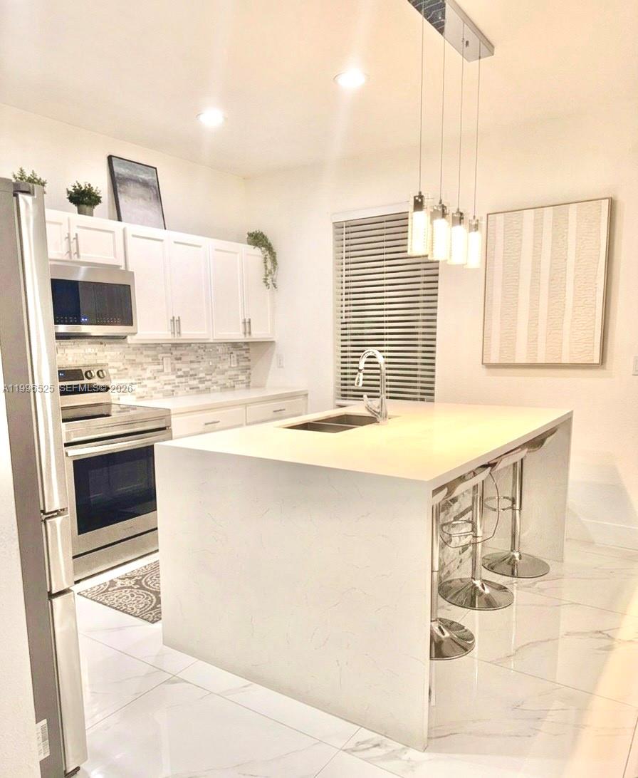 A modern kitchen features white cabinets, a quartz island with bar stools, and stainless appliances — 4237 SW 164th Path # 4237, Miami FL 33185, MIAMI, FL