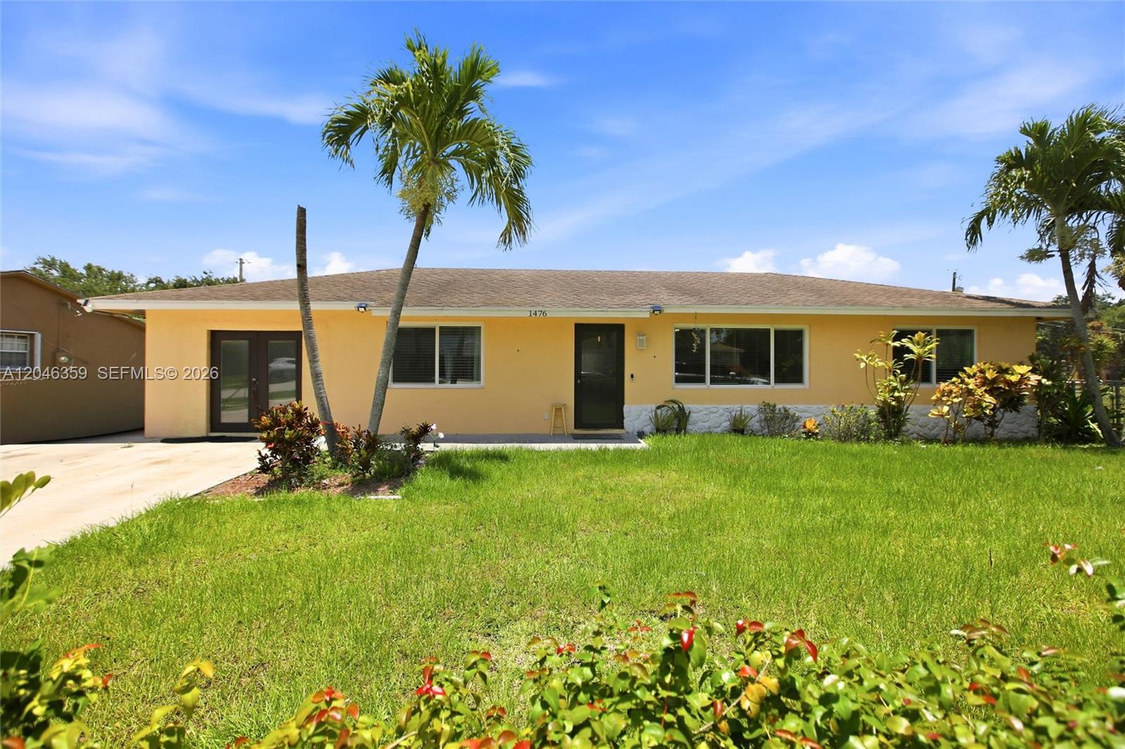 A single-story yellow house with a palm tree and a front lawn under a blue sky — 1476 N Mangonia Dr, West Palm Beach FL 33401, WEST PALM BEACH, FL