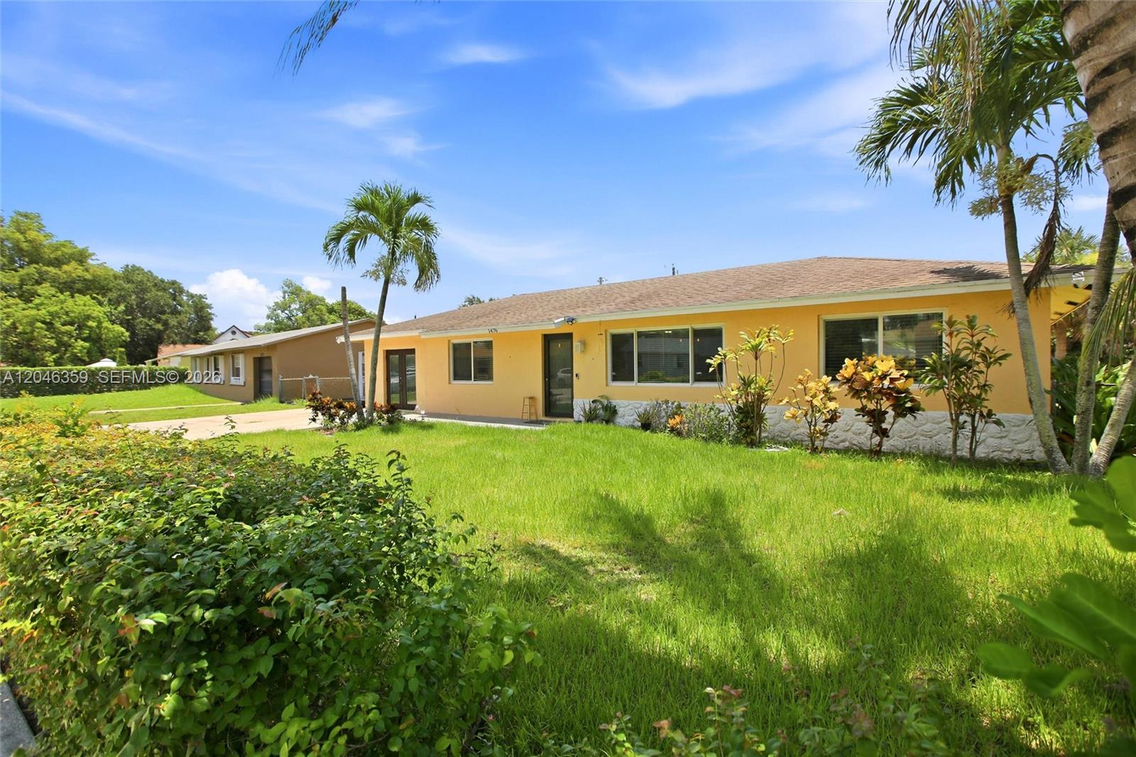 A yellow single-story house with a lawn and palm trees under a blue sky — 1476 N Mangonia Dr, West Palm Beach FL 33401, WEST PALM BEACH, FL