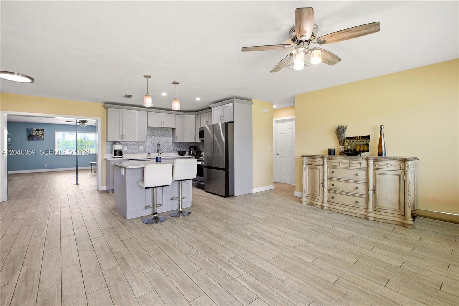 An open-concept kitchen features gray cabinetry, a central island with bar stools, and tile flooring — 1476 N Mangonia Dr, West Palm Beach FL 33401, WEST PALM BEACH, FL
