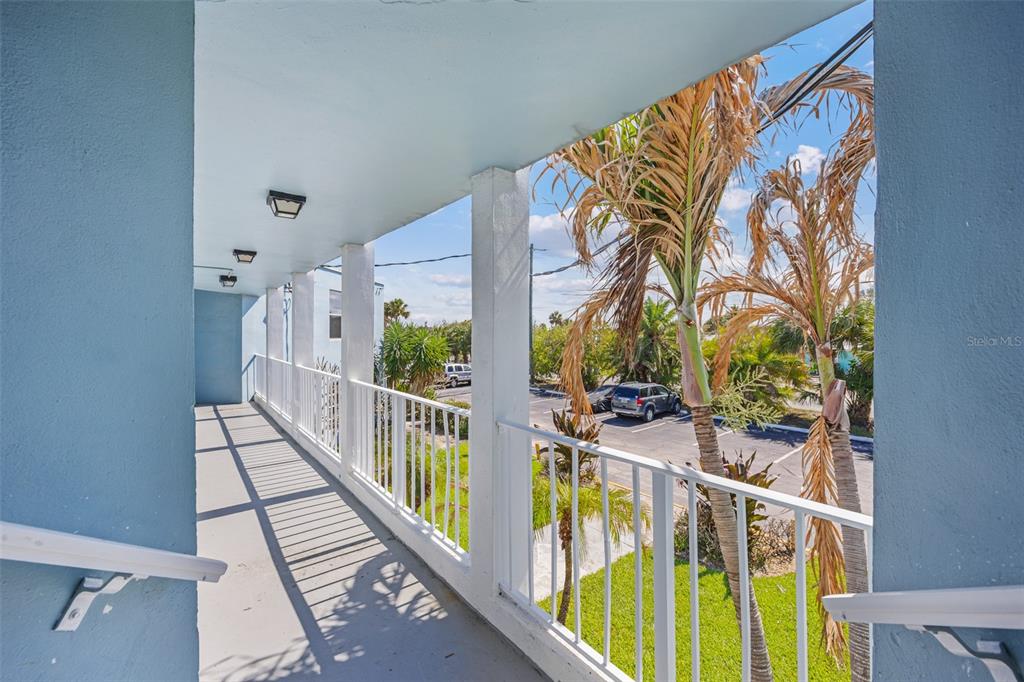 An outdoor covered walkway with white railings overlooks a parking lot and palm trees — 55 SEA PARK BOULEVARD UNIT 309, SATELLITE BEACH, FL