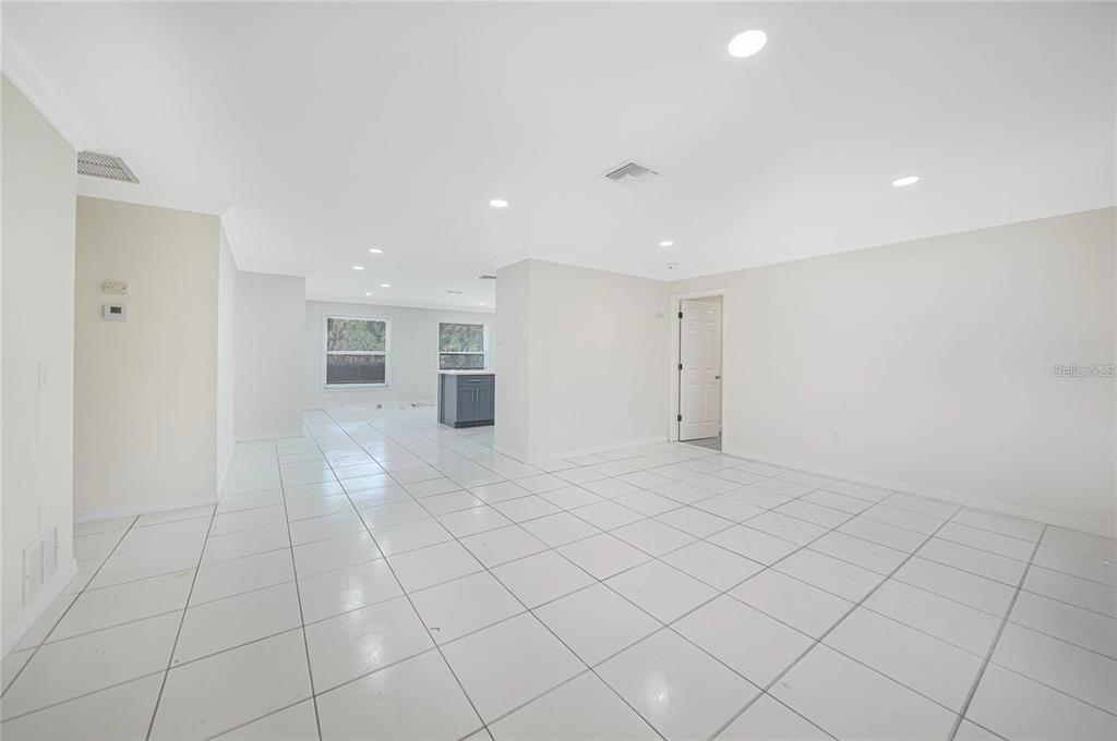 A bright, open-concept room features white tiled flooring, recessed lighting, and a kitchen in the background — 351 & 359 KINDRED BOULEVARD, PORT CHARLOTTE, FL