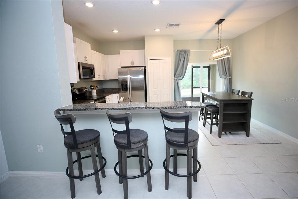 A kitchen with a breakfast bar, stainless steel appliances, and an adjacent dining area — 17620 NECTAR FLUME DRIVE, LAND O LAKES, FL