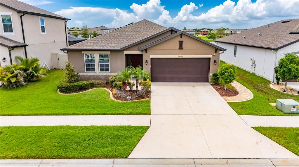 A single-story suburban house with a brown garage, tan siding, and a manicured front lawn — 11906 BAHIA VALLEY DRIVE, RIVERVIEW, FL