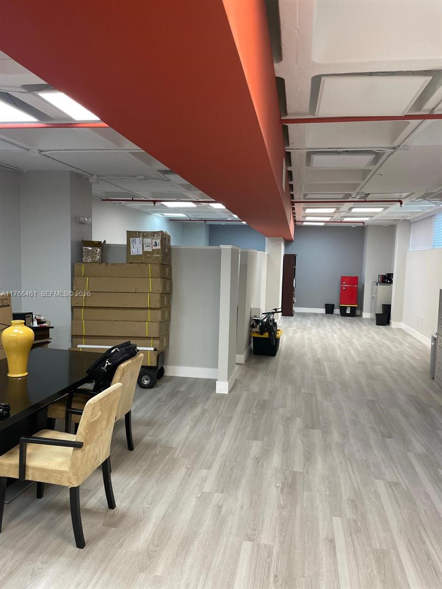 An office space features light wood-look flooring, a red ceiling beam, and stacked cardboard boxes — 4300 Biscayne Blvd # G06, Miami FL 33137, MIAMI, FL
