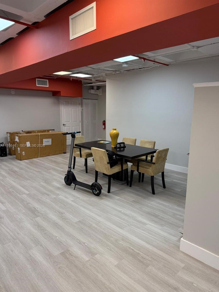 A dining area features a dark table with six chairs, light wood flooring, and a scooter — 4300 Biscayne Blvd # G06, Miami FL 33137, MIAMI, FL