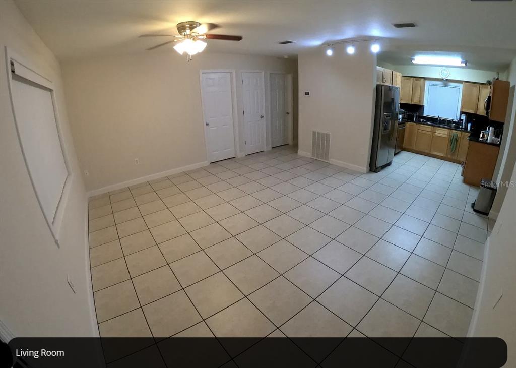 A tiled living room opens into a kitchen with wooden cabinets and stainless steel appliances — 1316 GRAYSON DRIVE, ORLANDO, FL