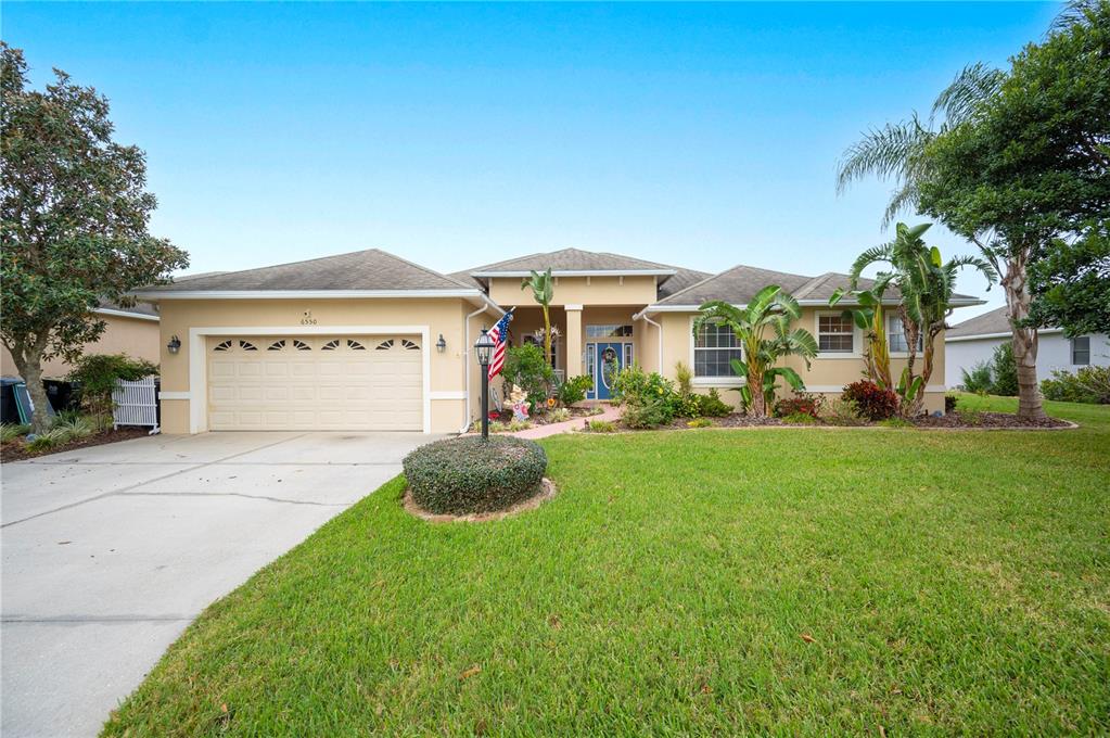 A single-story suburban house with a beige stucco exterior, a two-car garage, and landscaping — 6550 EVERGREEN PARK DRIVE, LAKELAND, FL