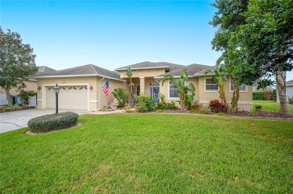 A single-story suburban house with a tan stucco exterior, a two-car garage, and landscaping — 6550 EVERGREEN PARK DRIVE, LAKELAND, FL