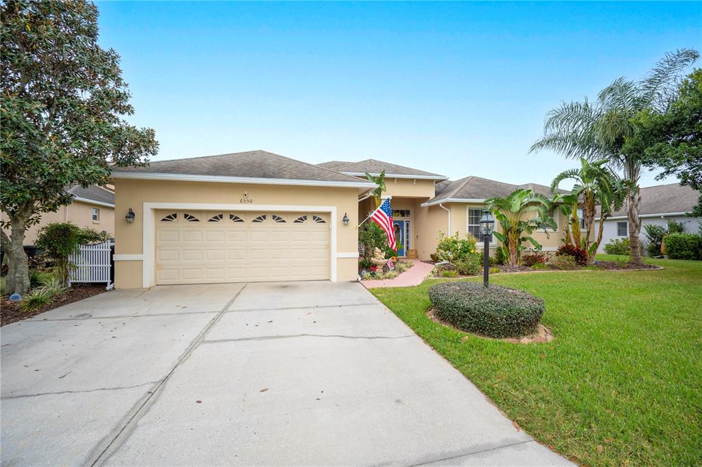 A single-story house with a beige stucco exterior, a two-car garage, and a front lawn — 6550 EVERGREEN PARK DRIVE, LAKELAND, FL