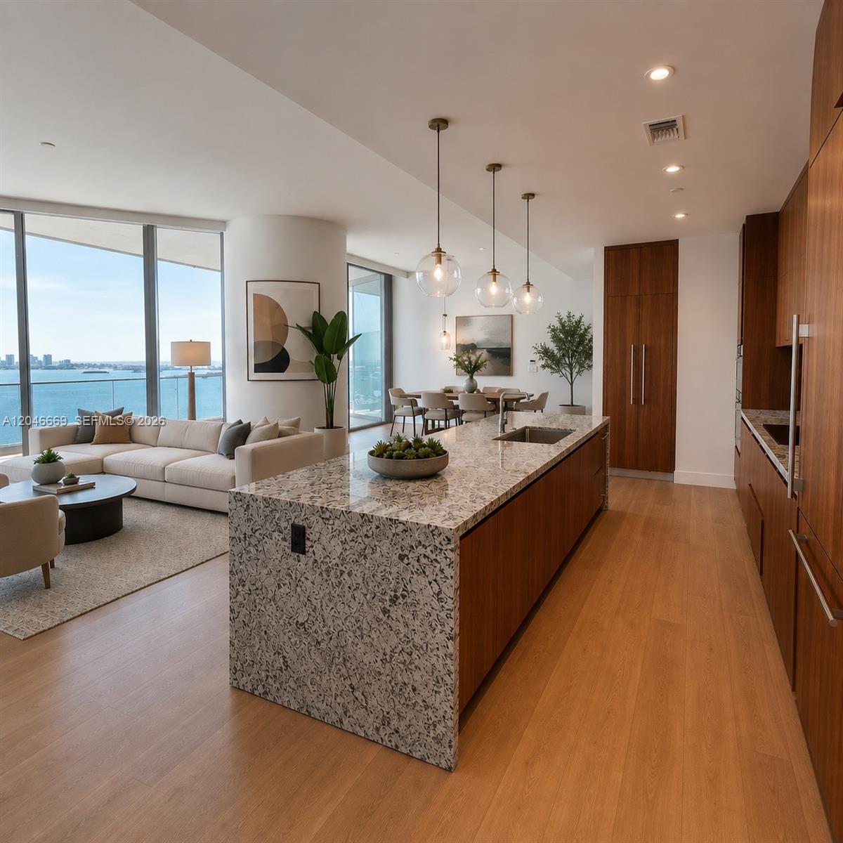 A modern open-concept kitchen and living area features a large stone island and ocean views — 175 SE 25th Road # 2804, Miami FL 33129, MIAMI, FL