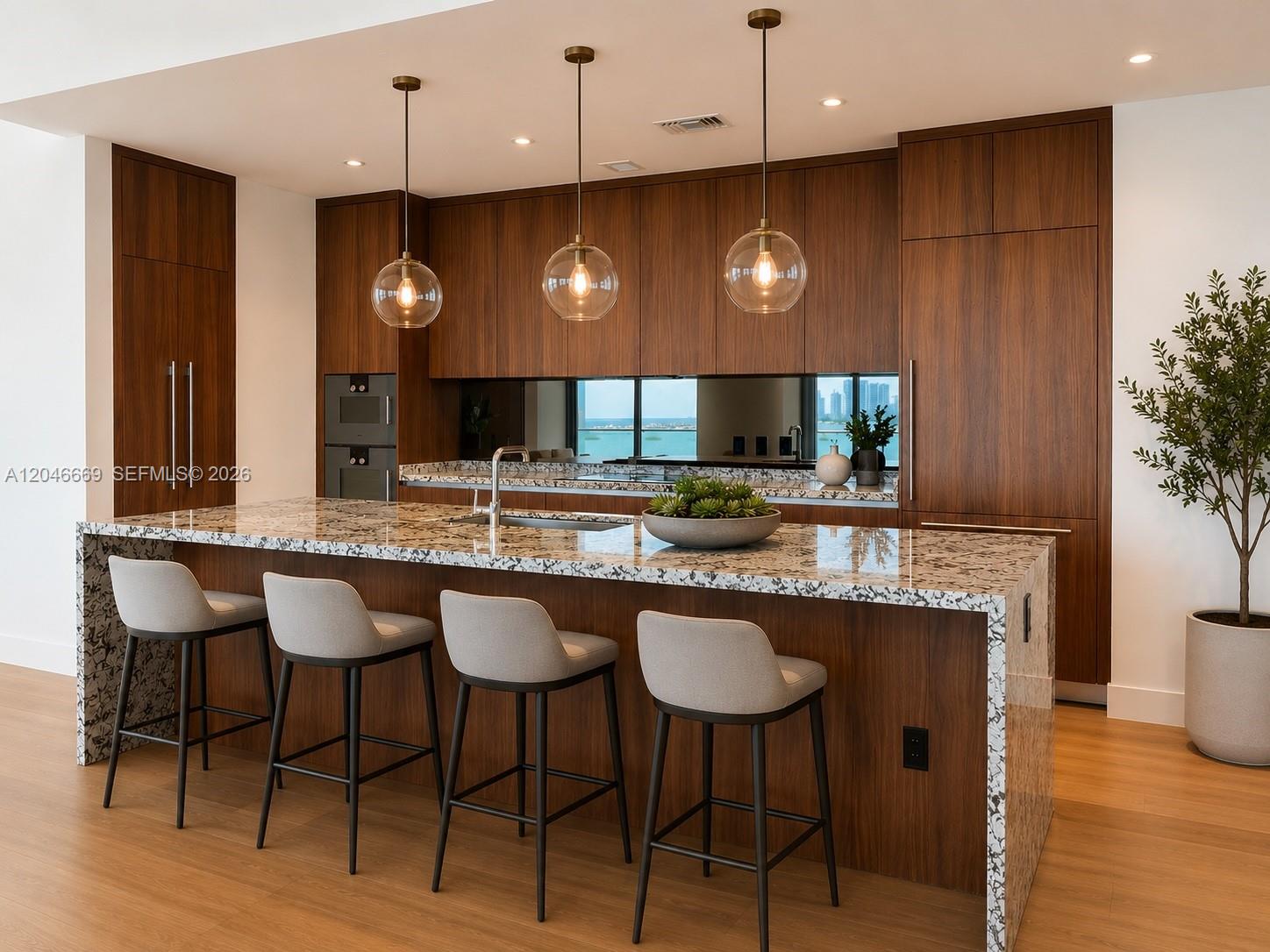 A modern kitchen features wood cabinetry, a granite waterfall island, and four gray bar stools — 175 SE 25th Road # 2804, Miami FL 33129, MIAMI, FL