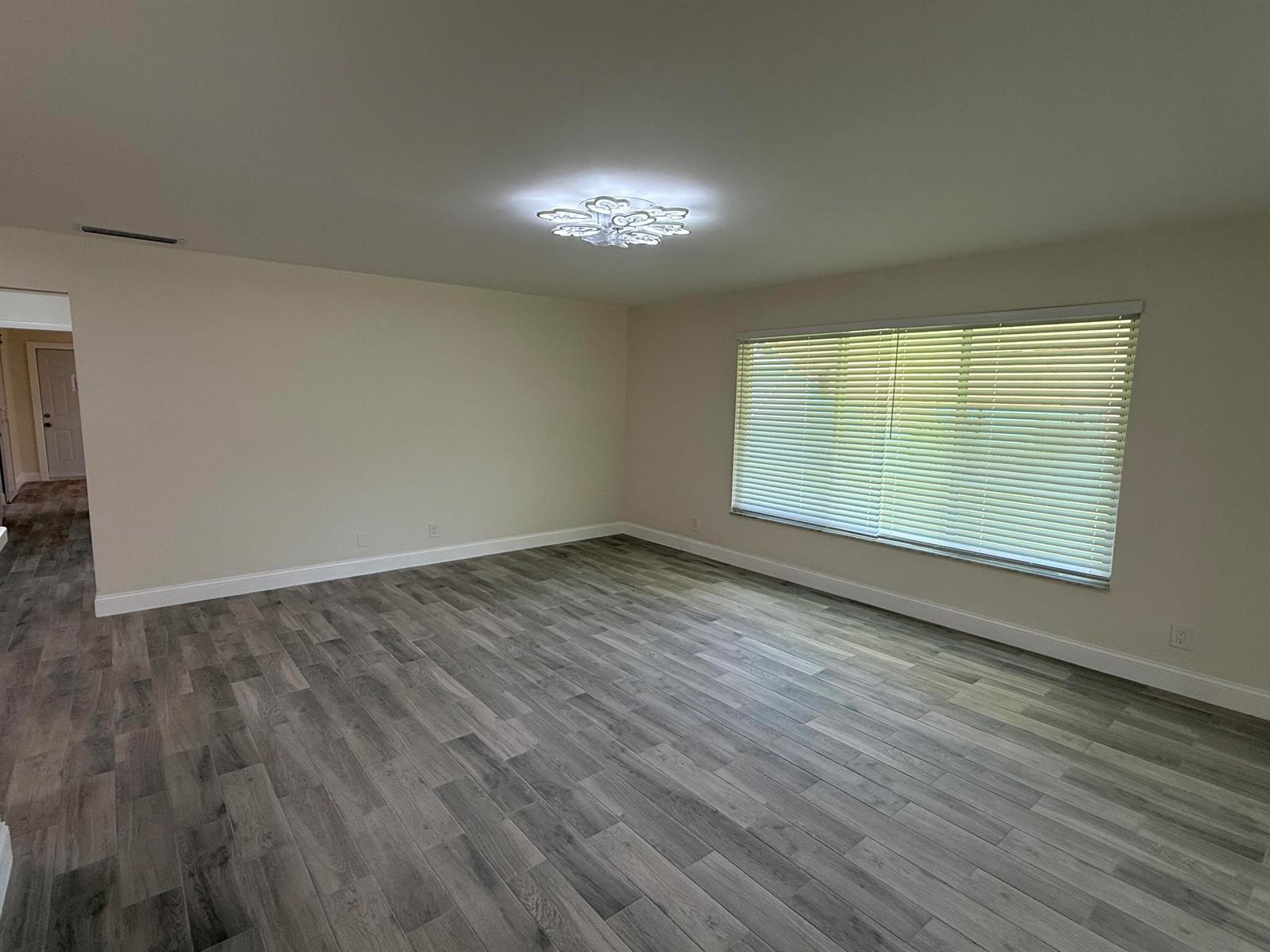 An empty room features light-colored walls, a modern ceiling light, and gray wood-look flooring — 255 South Boulevard # D, Boynton Beach FL 33435, BOYNTON BEACH, FL