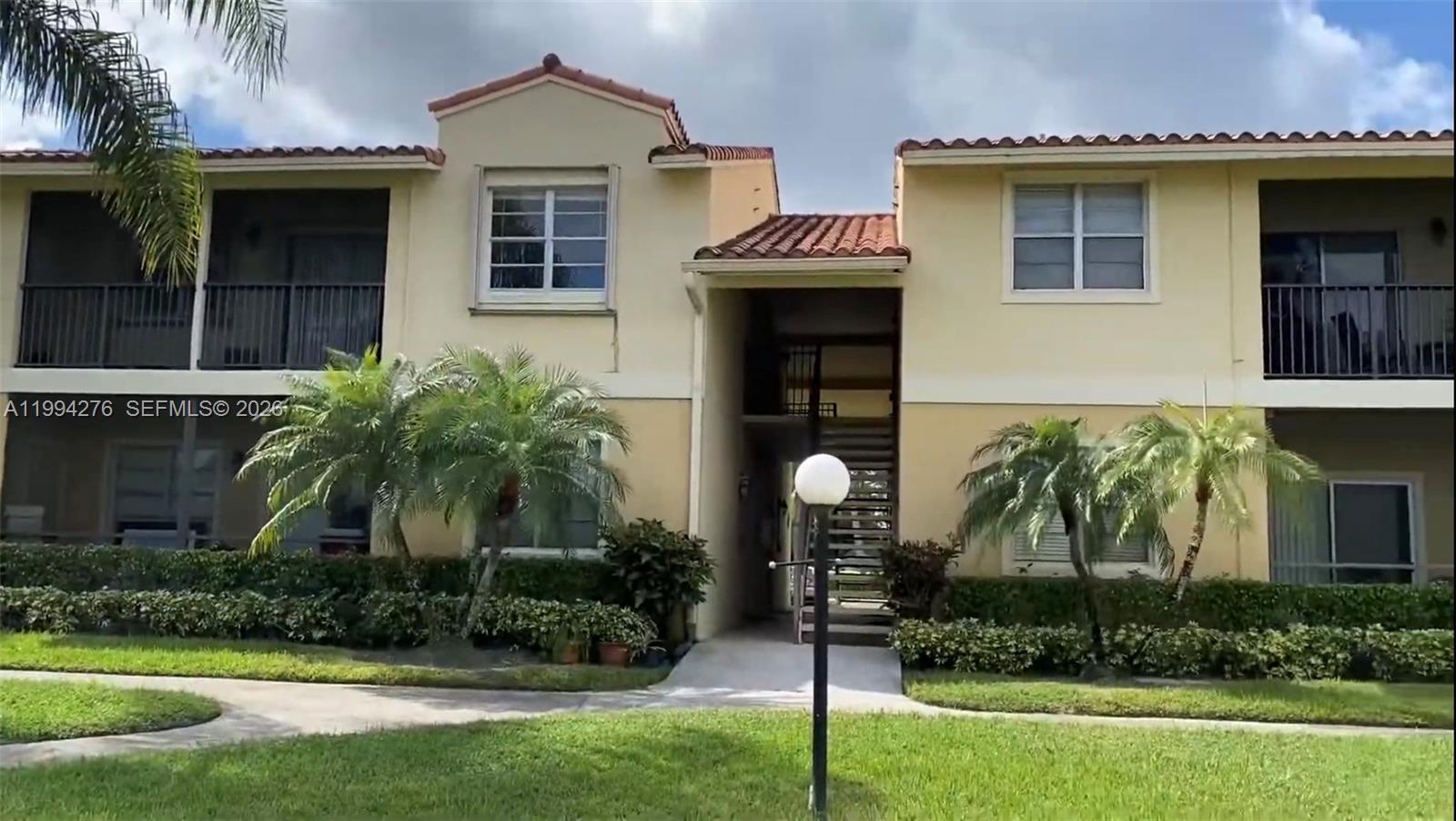A two-story apartment building with beige stucco walls, a tiled roof, and exterior staircases — 1261 SW 46th Ave # 2016, Pompano Beach FL 33069, POMPANO BEACH, FL