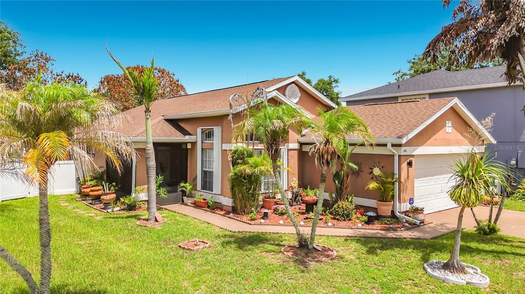 A single-story house with a tan stucco exterior, a garage, and several palm trees — 14208 AVONLEA COURT, ORLANDO, FL