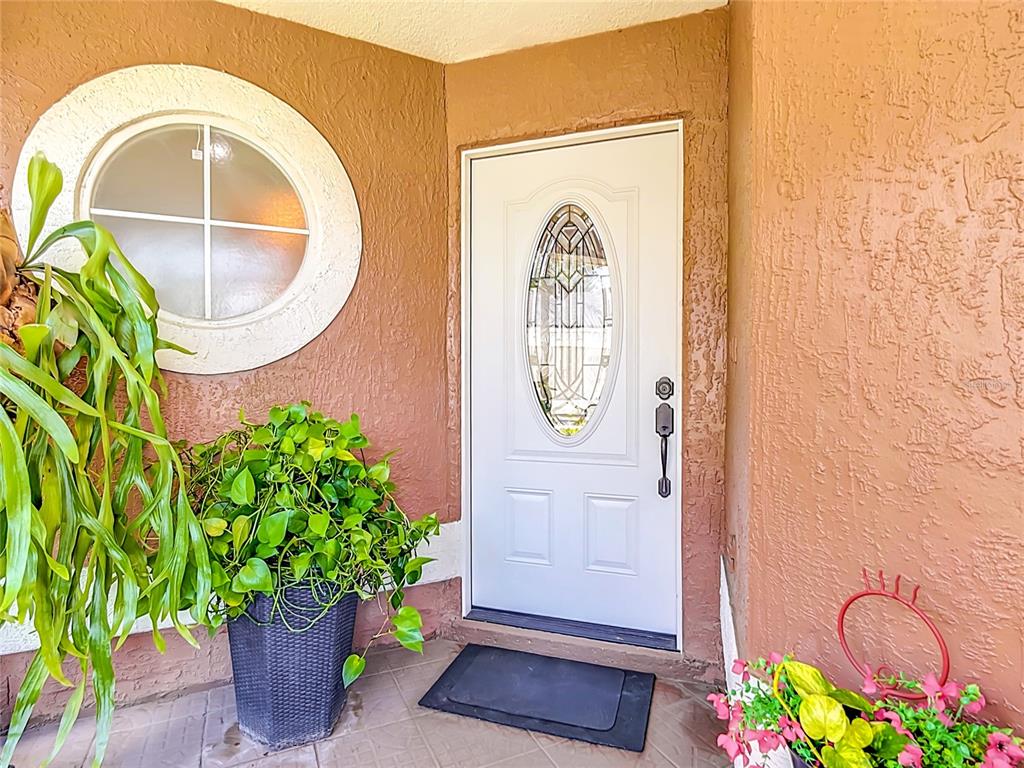 A white front door with a decorative oval window sits beside a round accent window — 14208 AVONLEA COURT, ORLANDO, FL