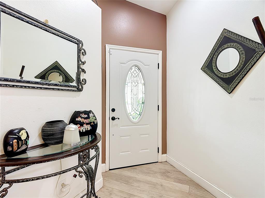 An entryway features a glass-topped console table, two decorative mirrors, and a white front door — 14208 AVONLEA COURT, ORLANDO, FL