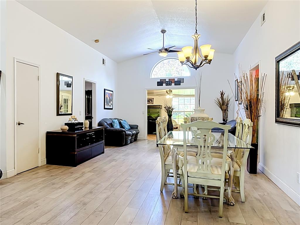 A dining area with a glass table and chairs opens into a living room — 14208 AVONLEA COURT, ORLANDO, FL