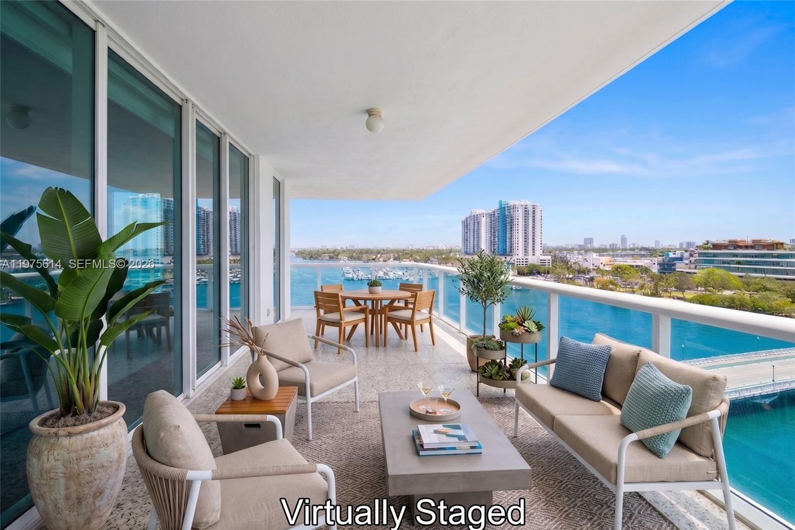 A spacious balcony features outdoor furniture, a concrete coffee table, and panoramic water views — 10 Venetian Way # 904, Miami Beach FL 33139, MIAMI BEACH, FL