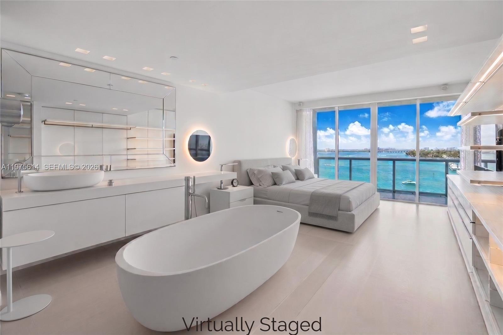 This virtually staged bedroom features an open-concept bathroom, a soaking tub, and floor-to-ceiling windows — 10 Venetian Way # 904, Miami Beach FL 33139, MIAMI BEACH, FL