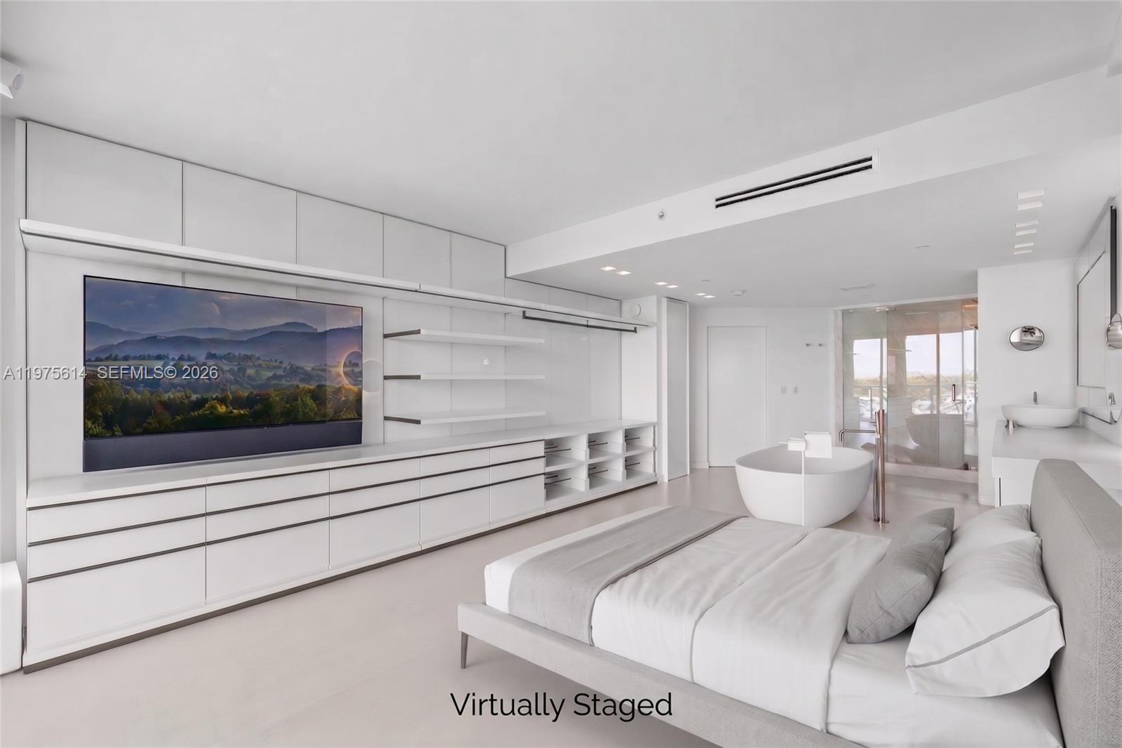 A modern, minimalist bedroom features a large television, built-in cabinetry, and an open-concept soaking tub — 10 Venetian Way # 904, Miami Beach FL 33139, MIAMI BEACH, FL