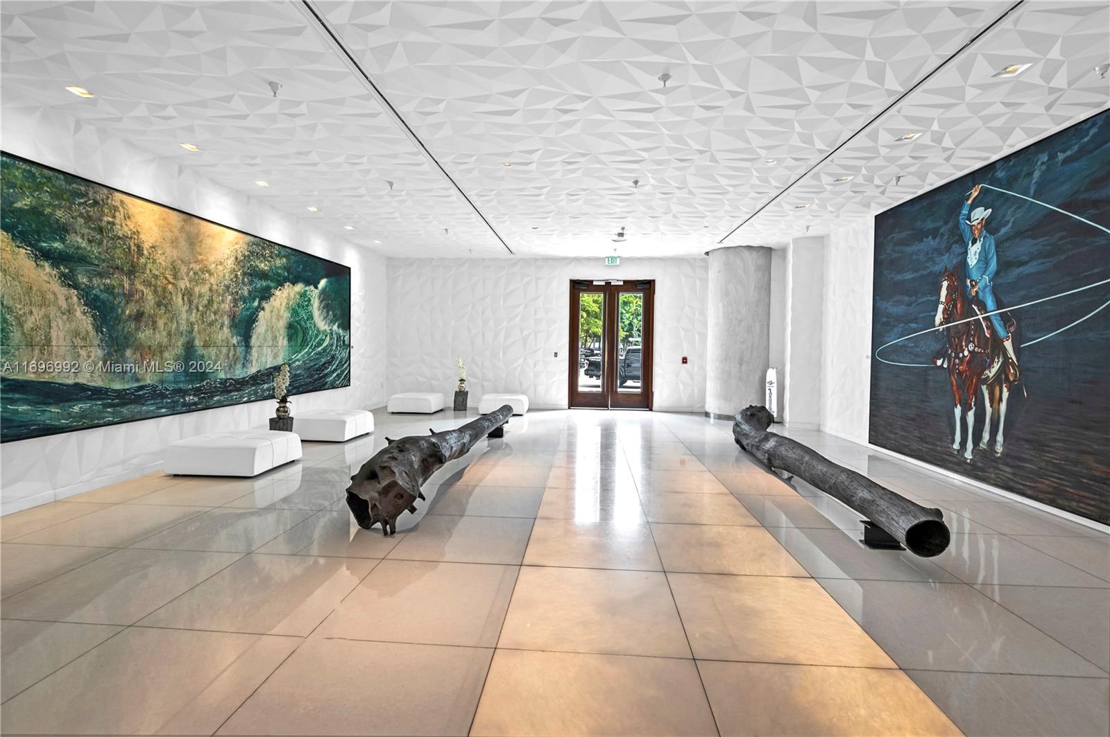 A modern lobby features white geometric walls, two large paintings, and two dark log sculptures — 1300 S Miami Ave # 3704, Miami FL 33130, MIAMI, FL