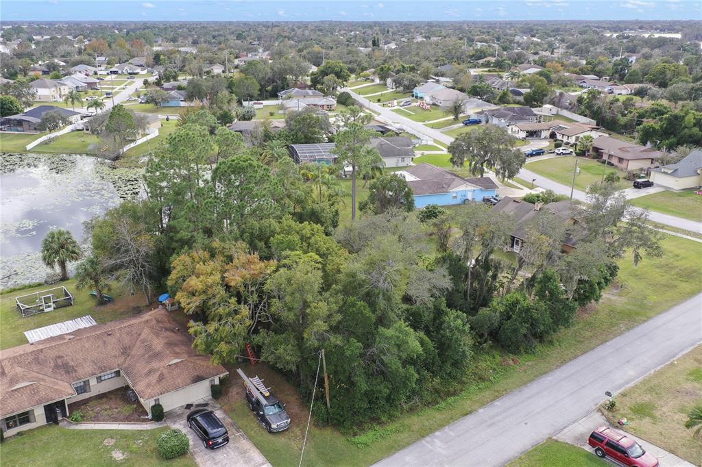An aerial view shows a residential neighborhood with houses, a pond, and dense trees — 2145 MONTECITO AVENUE, DELTONA, FL