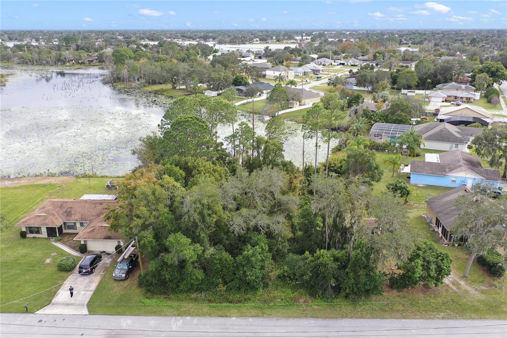 An aerial view shows a house with a driveway next to a wooded vacant lot — 2145 MONTECITO AVENUE, DELTONA, FL